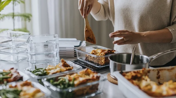 Femme pesant des boîtes à lunch dans le cadre d'une préparation de repas sains