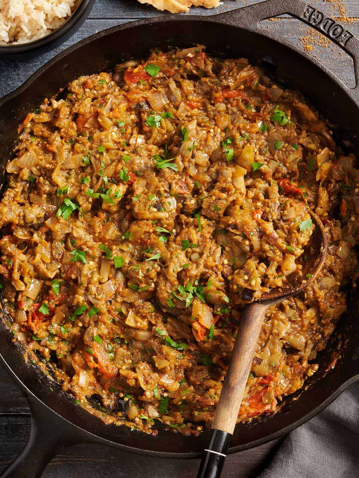 curry d'aubergines dans une poêle avec une cuillère en ramassant