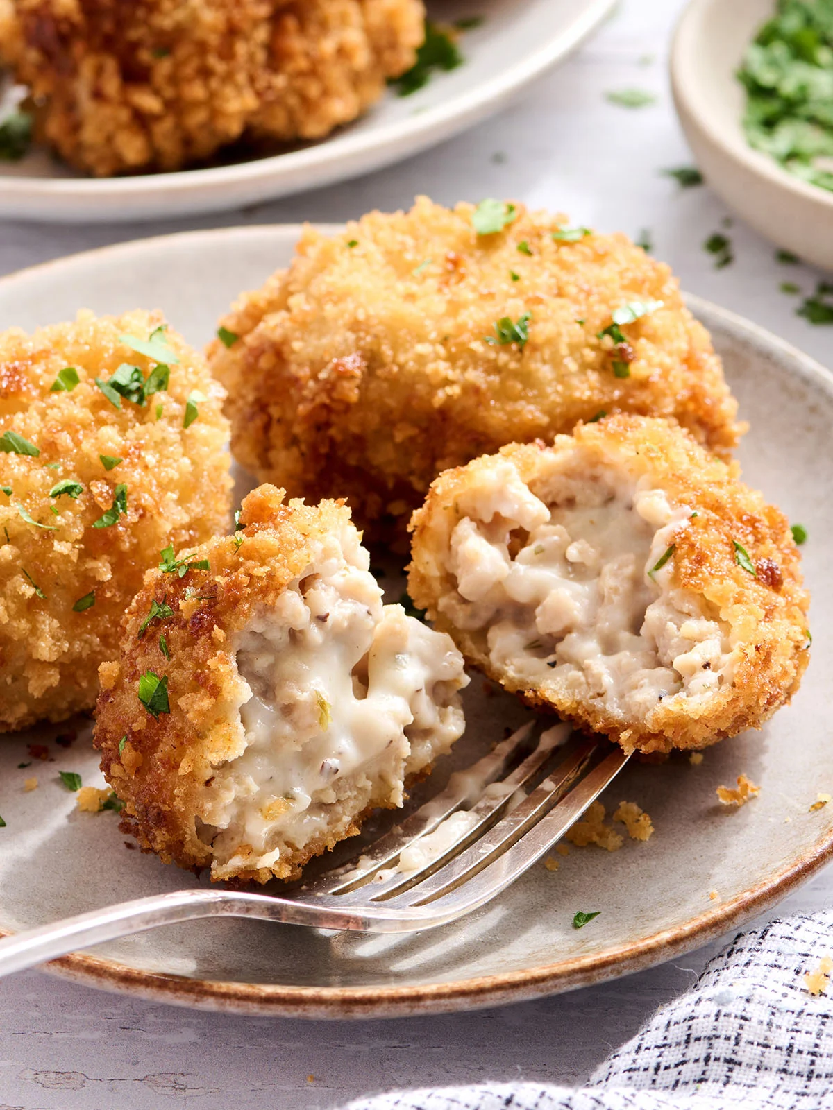 Vue latérale des croquettes de poulet sur une assiette dont une coupée en deux.
