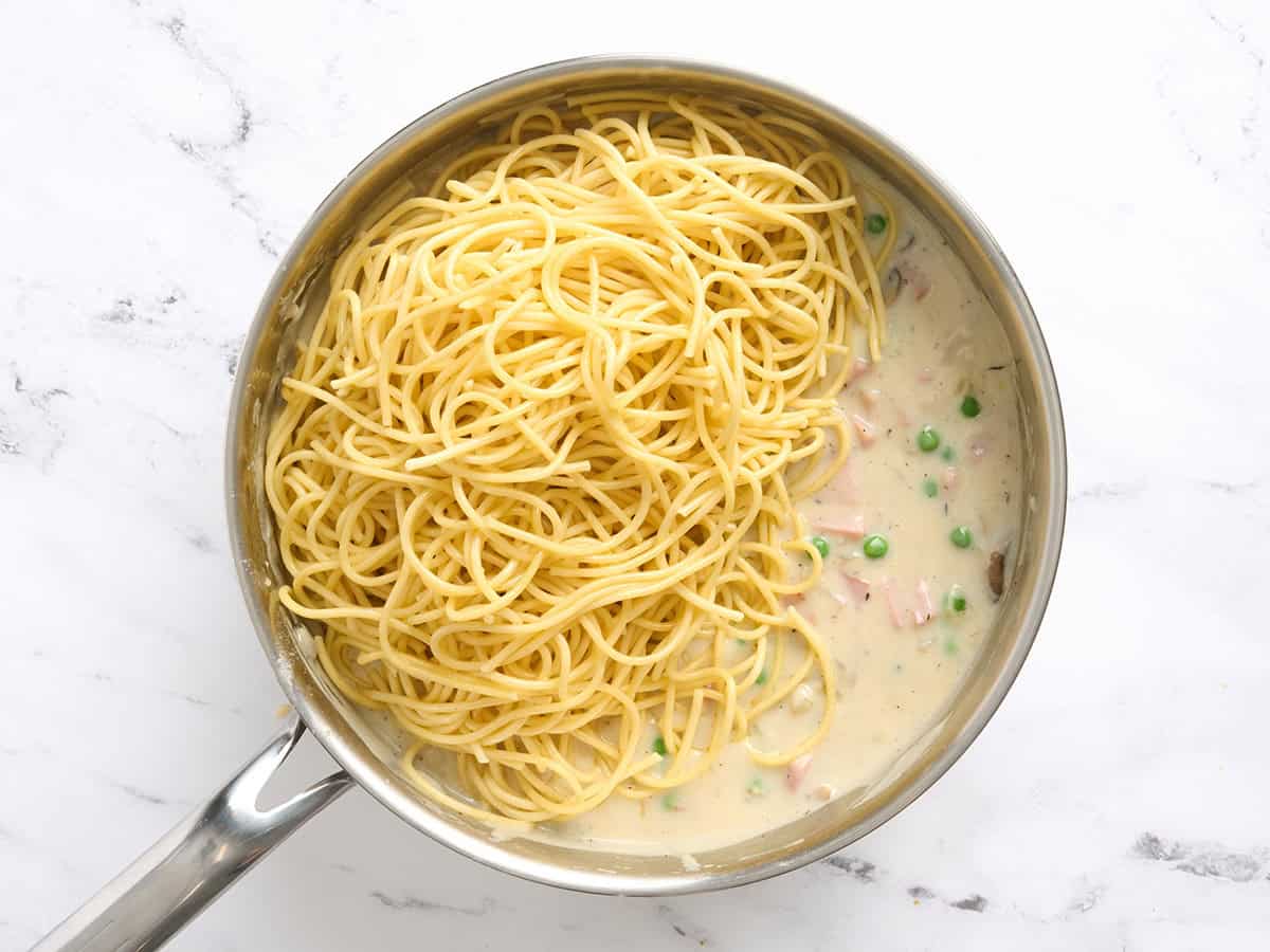 Spaghetti ajouté à une poêle de sauce crémeuse au jambon tetrazzini.