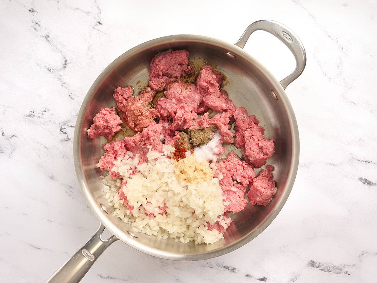 Oignon émincé, bœuf haché et épices dans une poêle.