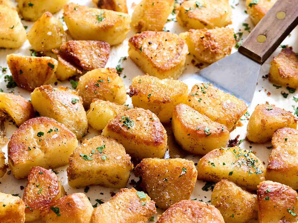 Oven roasted potatoes on a baking sheet with a spatula.