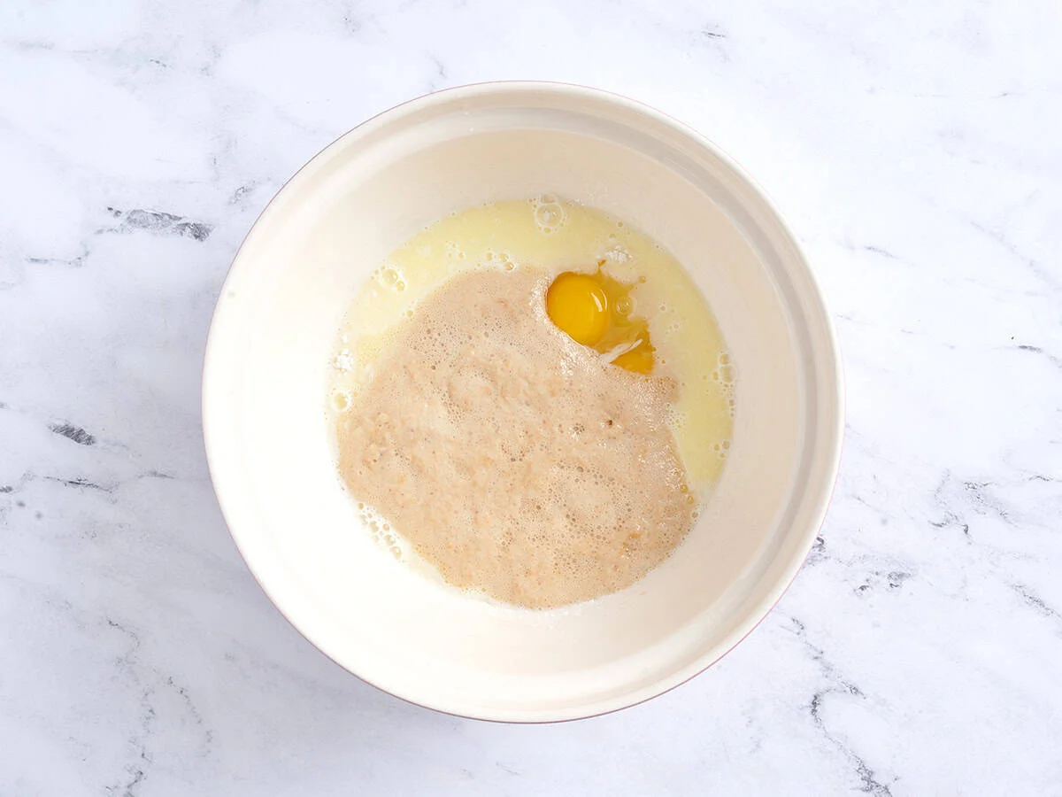 Ajouter le lait, la levure et les œufs à la farine et au sucre. 