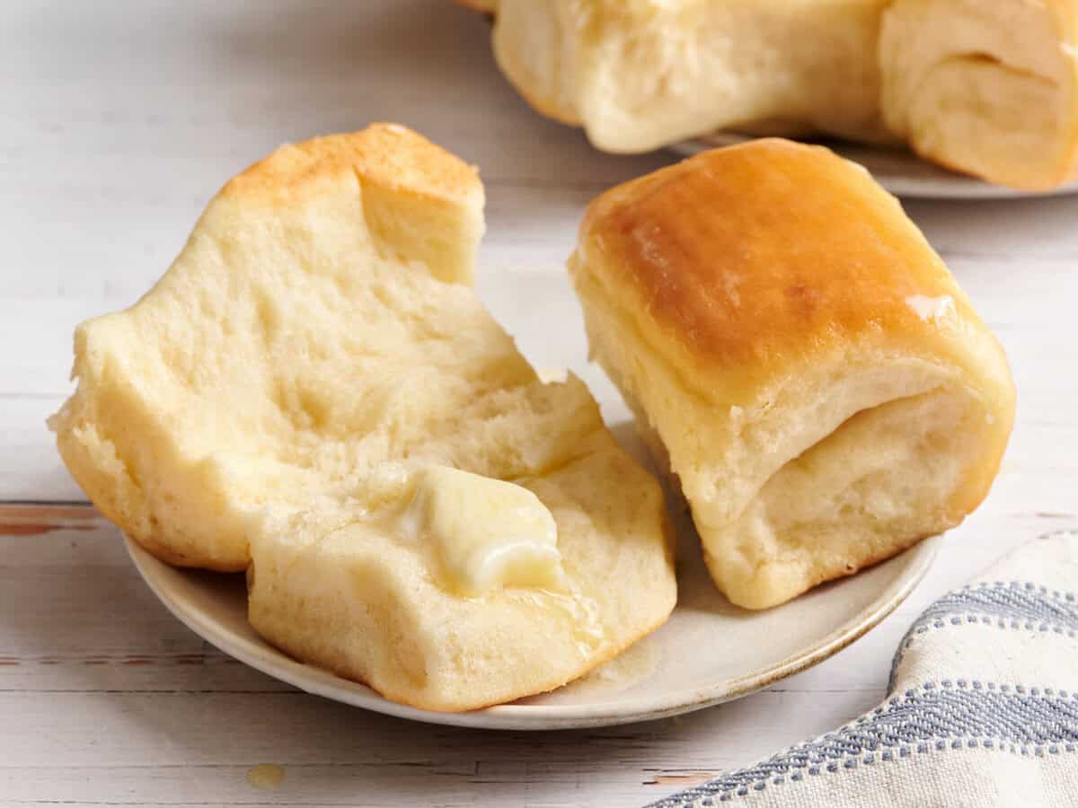 Parker Roll coupé en deux avec une noisette de beurre sur une assiette blanche. 