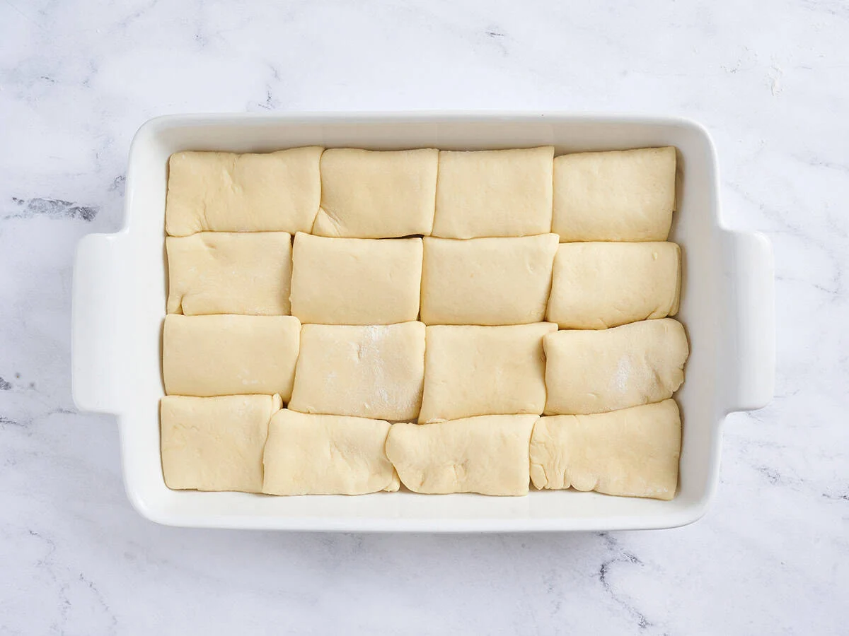 16 petits pains dans le plat allant au four prêts pour la deuxième levée. 