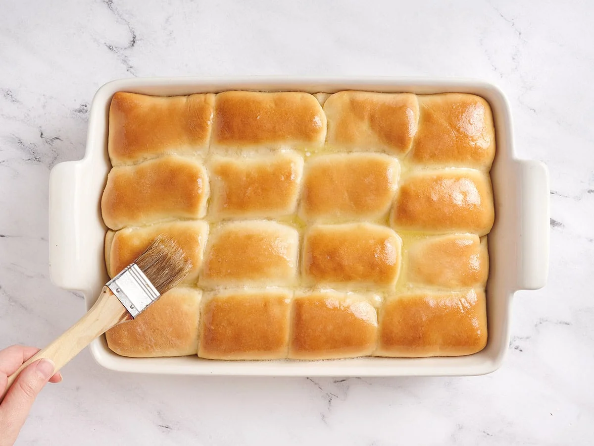 Badigeonner le dessus des petits pains cuits avec du beurre.