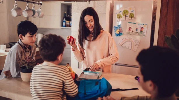 Mère préparant des boîtes à lunch avec des aliments sains et des collations pour ses fils avant d'aller à l'école