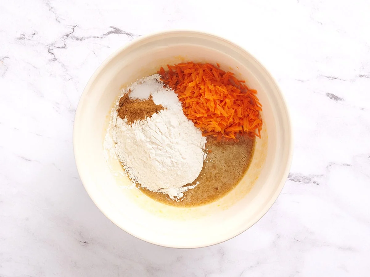 Farine, épices, carottes râpées et pâte à gâteau dans un bol.