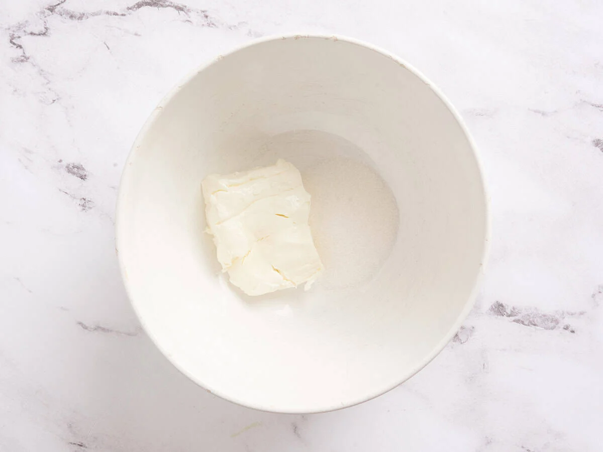 Sucre et fromage à la crème ajoutés dans un bol à mélanger.