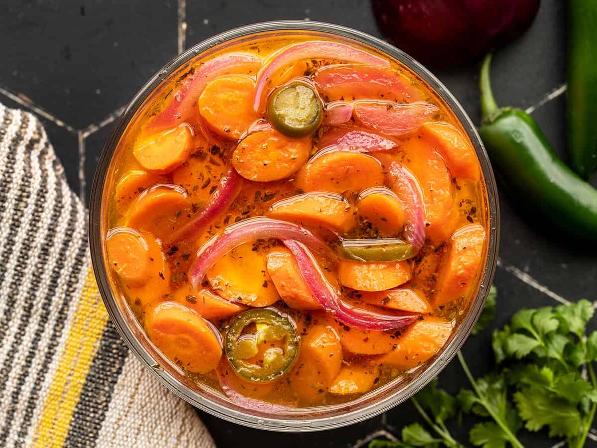 Vue aérienne de carottes marinées épicées dans un bol en verre.
