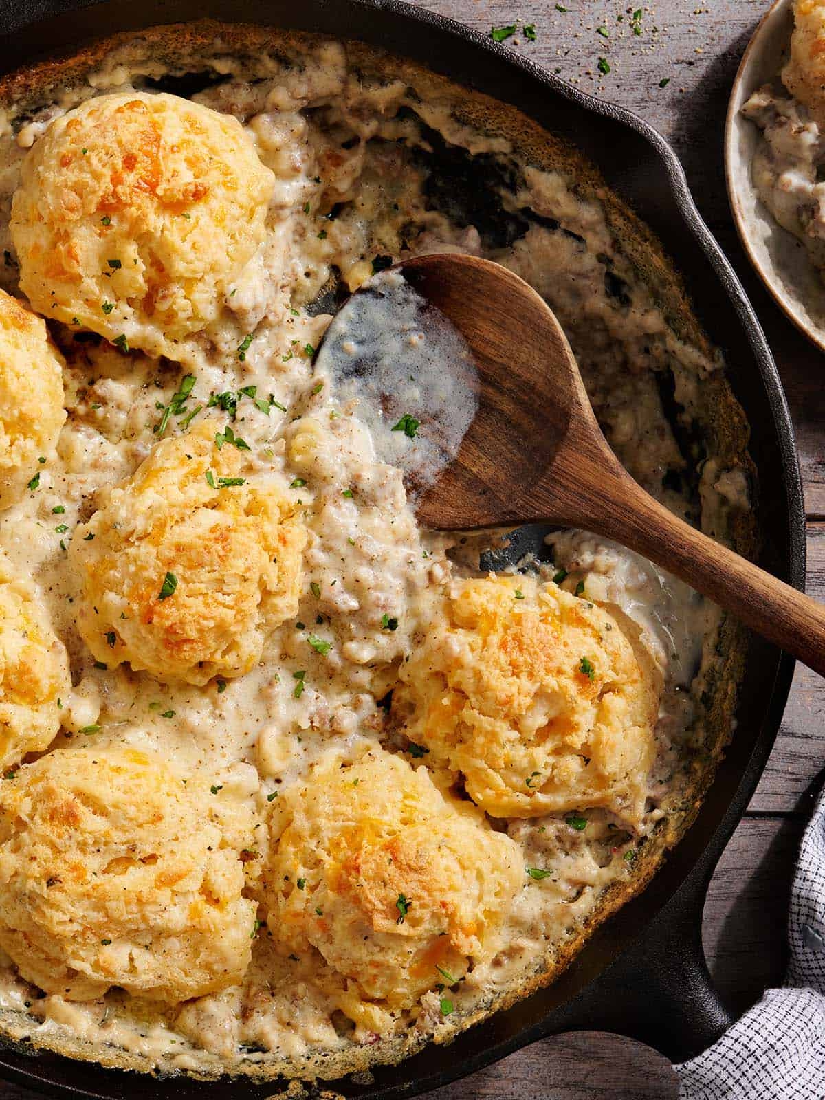 Vue aérienne d'une cuisson de biscuits et de sauce dans une poêle avec une cuillère en bois.