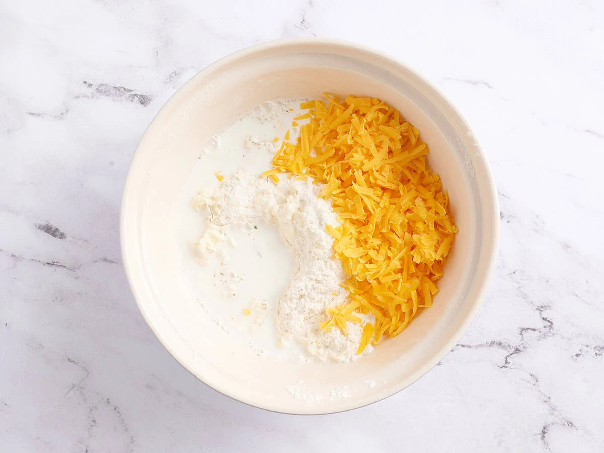 Lait et fromage râpé dans un bol.