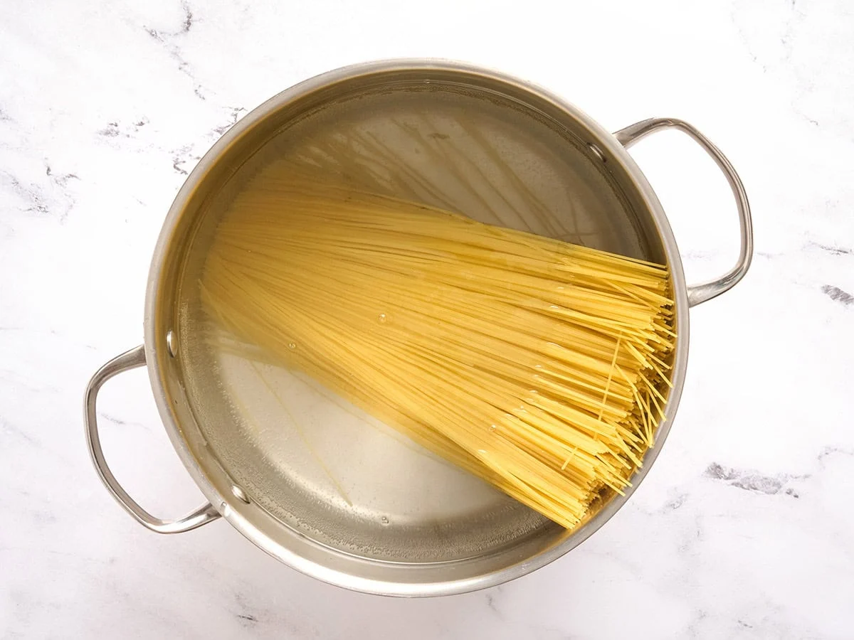 Pâtes aux cheveux d'ange ajoutées à une casserole d'eau.