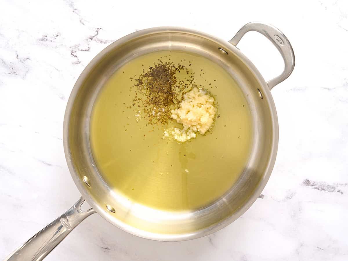 Ail, herbes et huile dans une poêle.