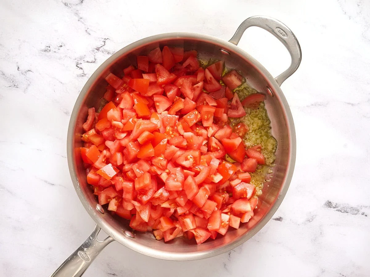 Tomates en dés ajoutées dans une poêle.
