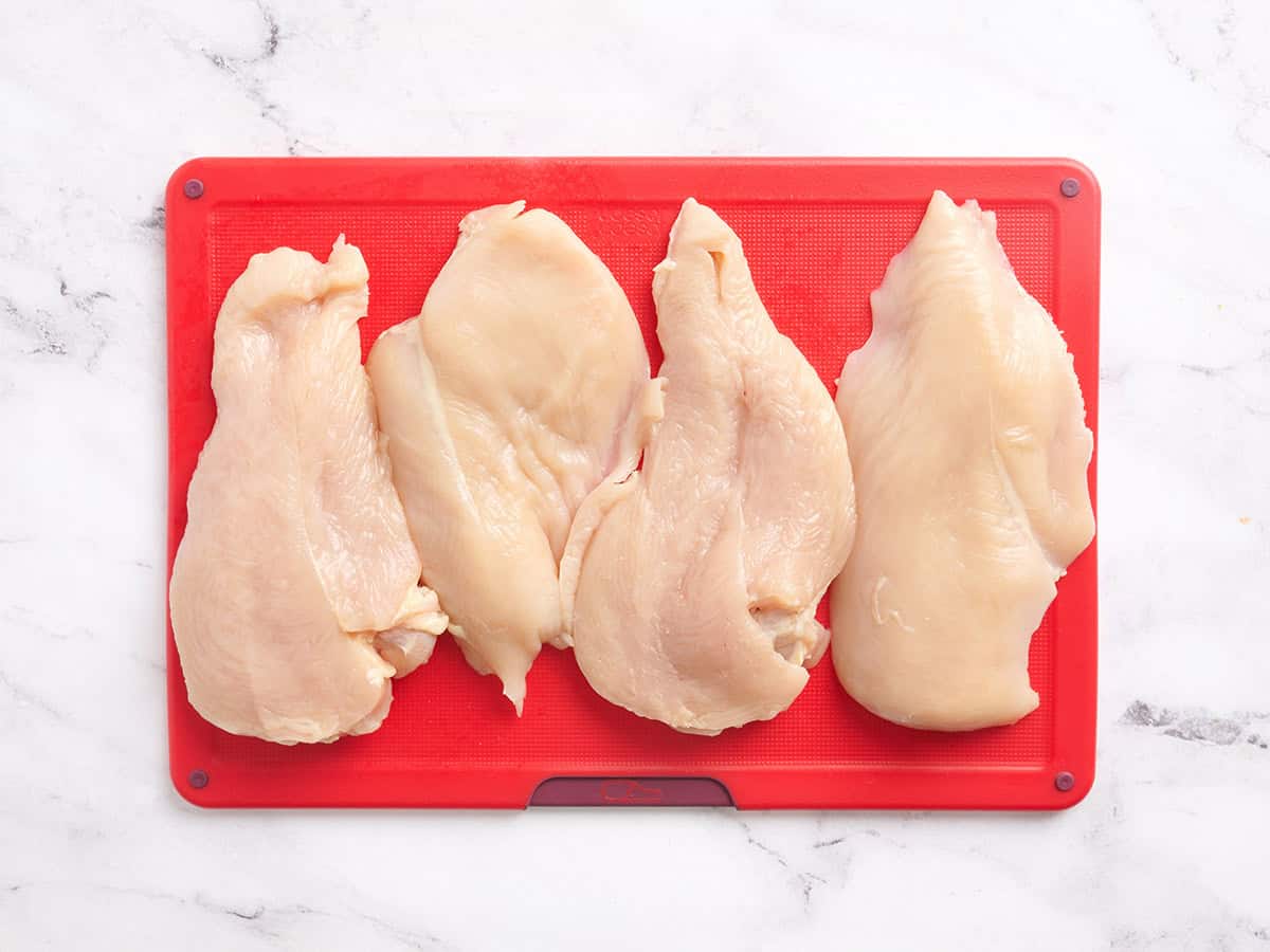 Deux poitrines de poulet en filets sur une planche à découper.