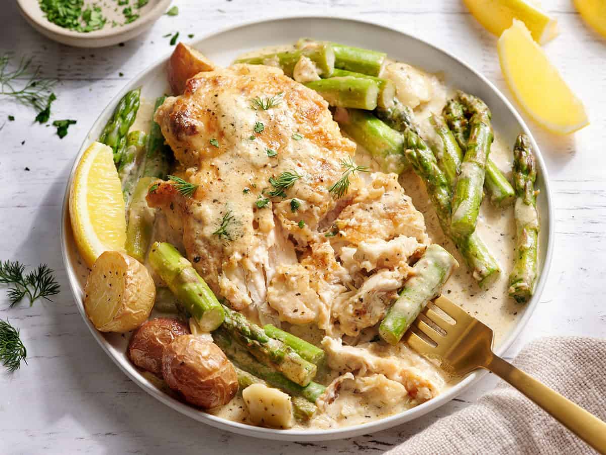 Side view of creamy asparagus chicken on a plate with a fork.