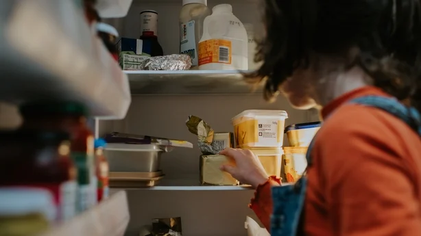 Un enfant ouvre un réfrigérateur et fouille à l’intérieur.