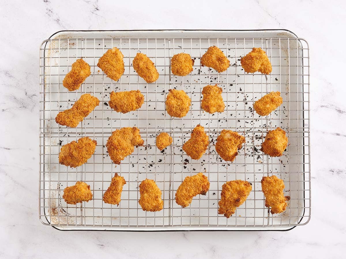 Nuggets de poulet faits maison finis sur une grille après la cuisson.
