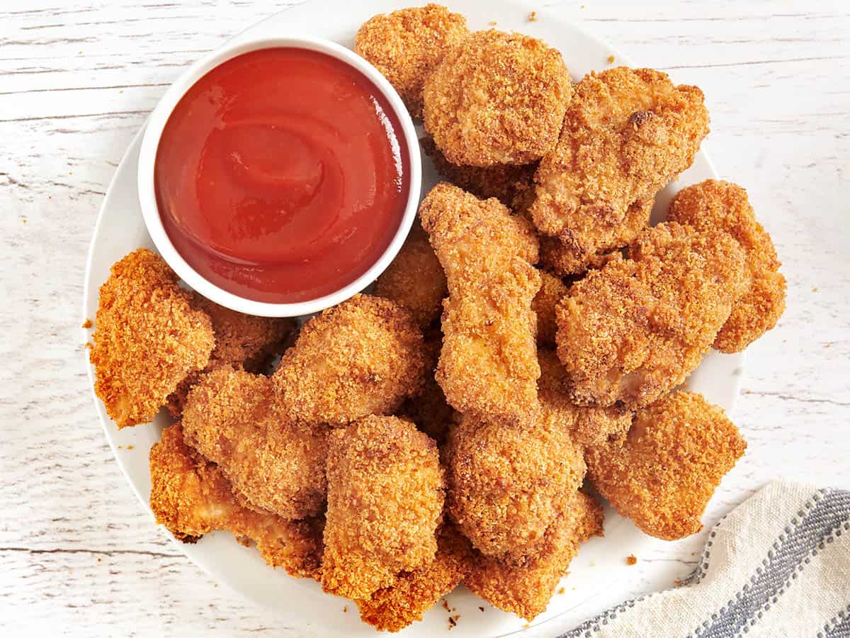 Vue aérienne de nuggets de poulet cuits au four sur une assiette avec un pot de ketchup.