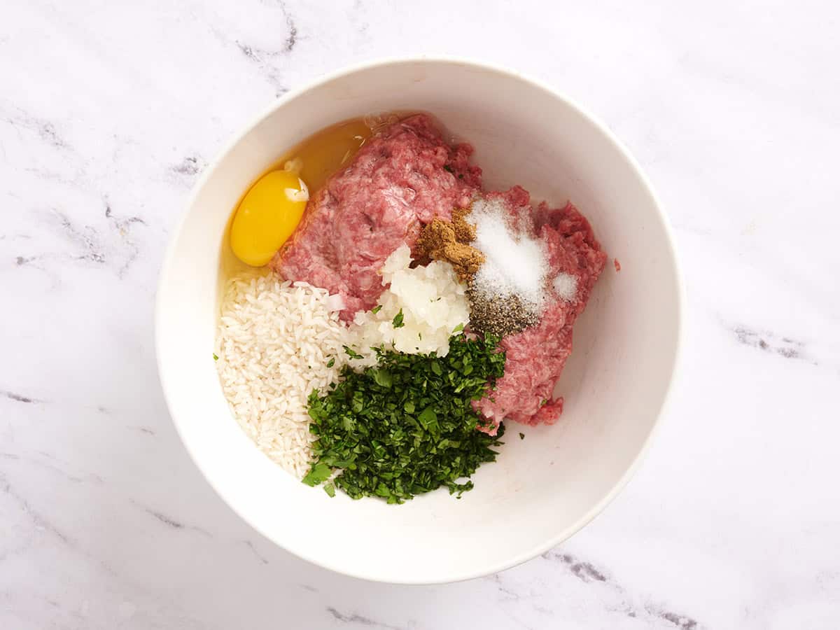 Bœuf haché, riz blanc non cuit, œuf, oignon, assaisonnements et coriandre fraîche dans un bol à mélanger.