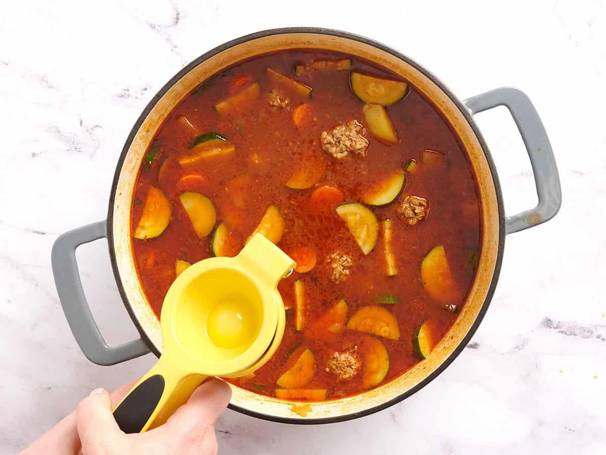 Un demi-citron vert frais pressé dans une casserole de soupe aux boulettes de viande mexicaine.