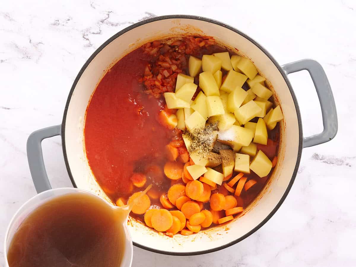 Bouillon, sauce tomate, légumes et épices dans une casserole.