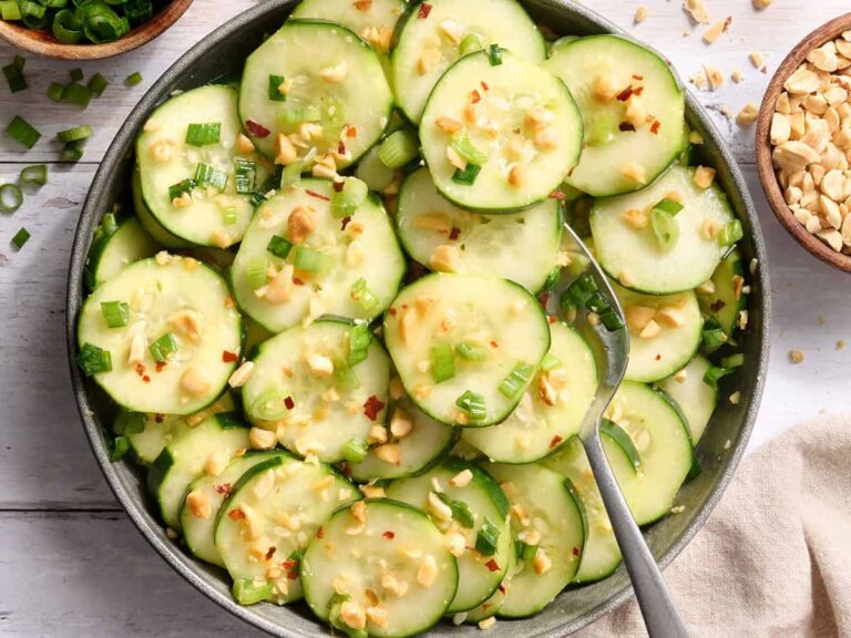 Overhead view of a bowl of sesame cucumber salad with a spoon.