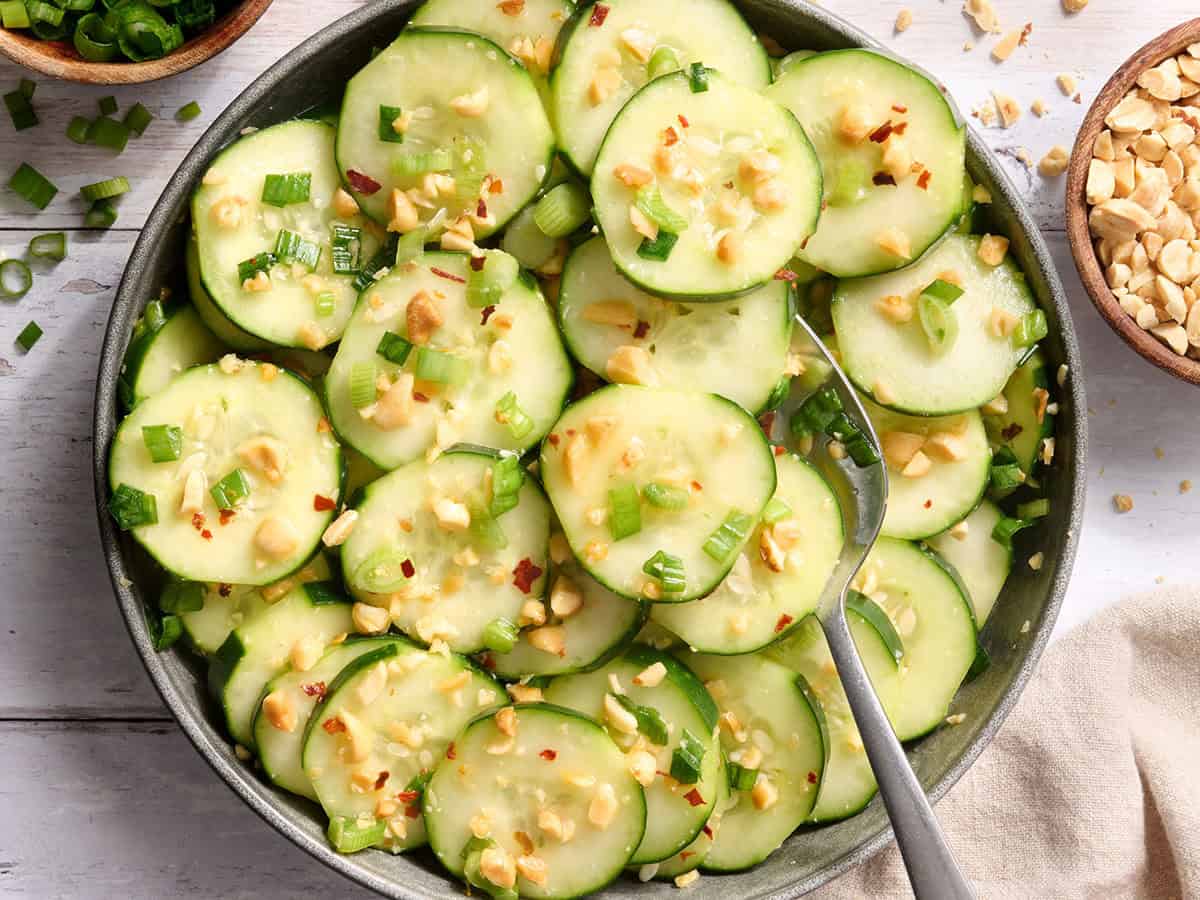 Overhead view of a bowl of sesame cucumber salad with a spoon.