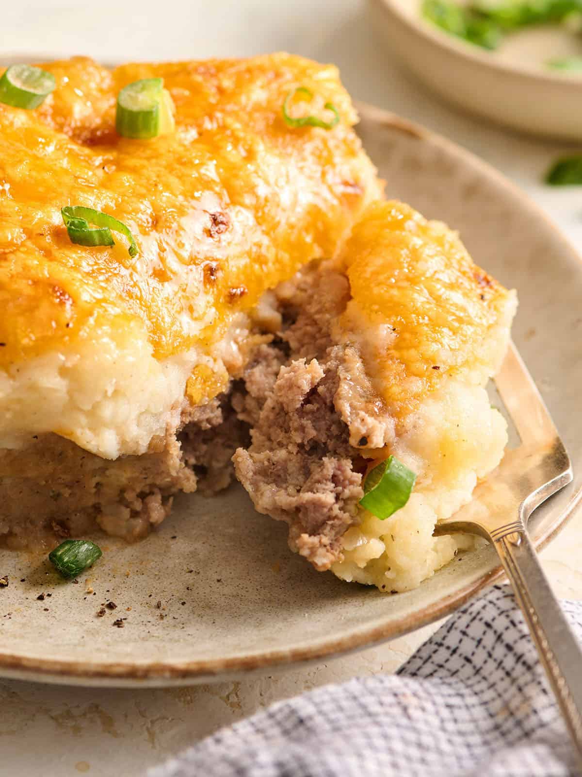 Vue latérale d'une tranche de cocotte de pain de viande sur une assiette avec une fourchette.