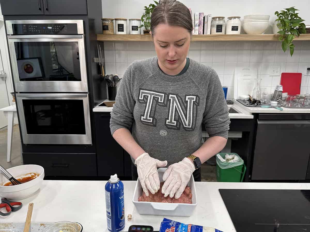 Une femme pressant le mélange de pain de viande dans une cocotte.