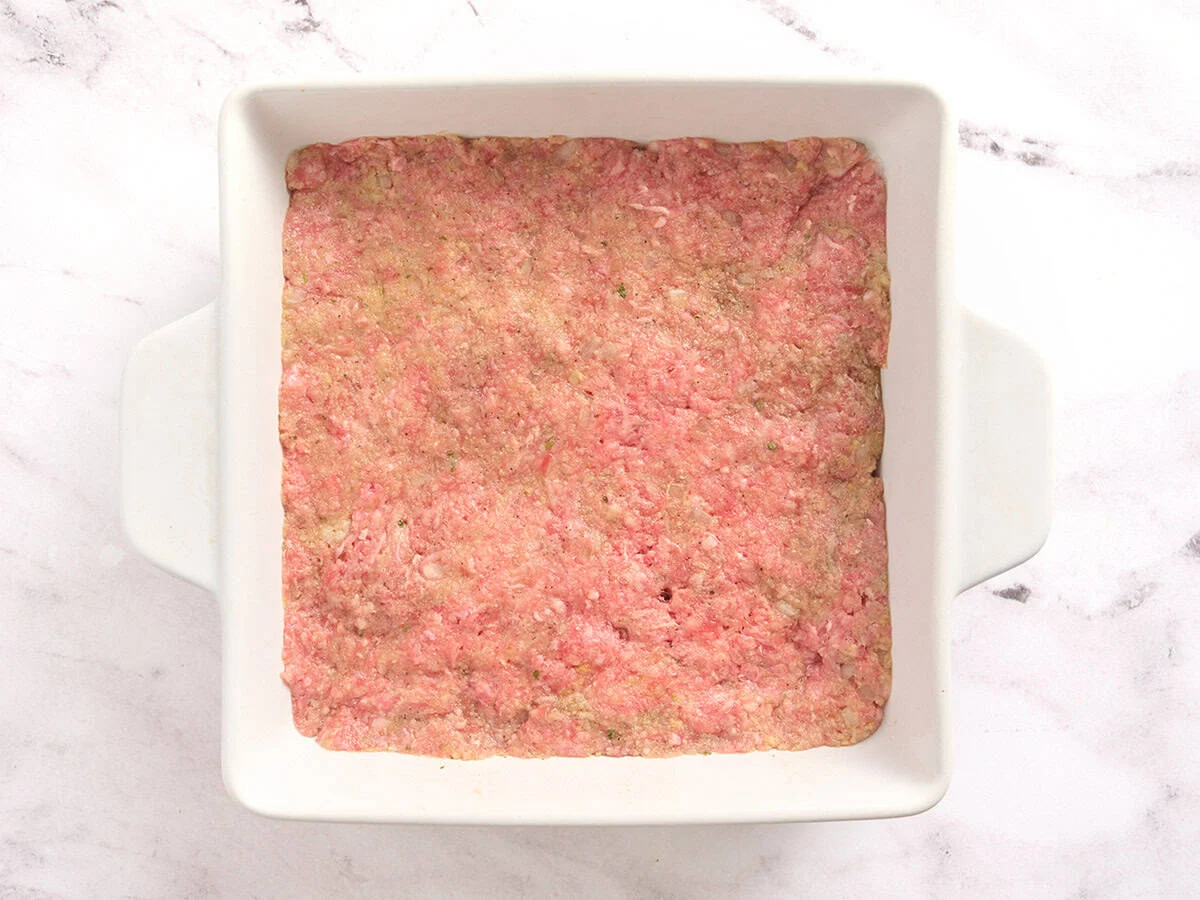 Mélange de pain de viande dans un plat carré allant au four.