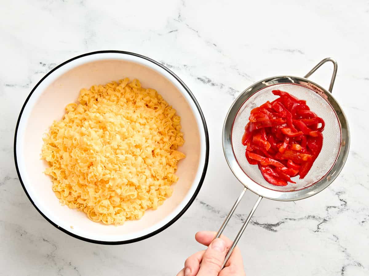 Un bol de cheddar râpé et de piments égouttés.