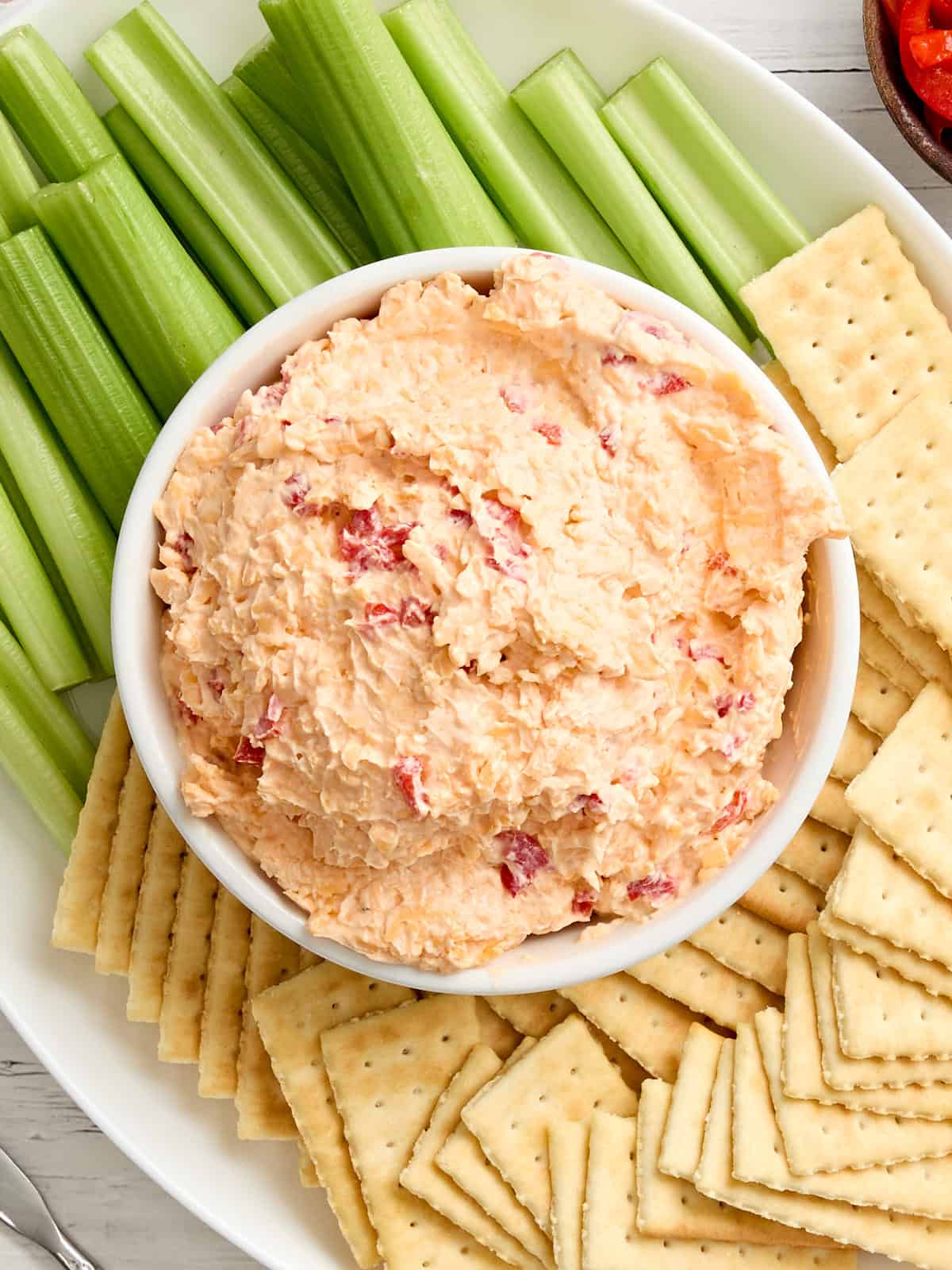 Vue aérienne d'un bol de fromage piment avec céleri et craquelins.