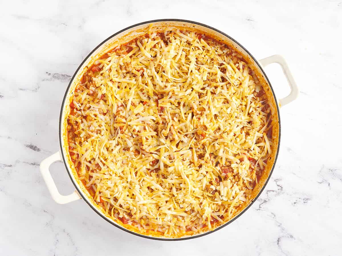 Fromage râpé ajouté à une poêle à poivre farcie.