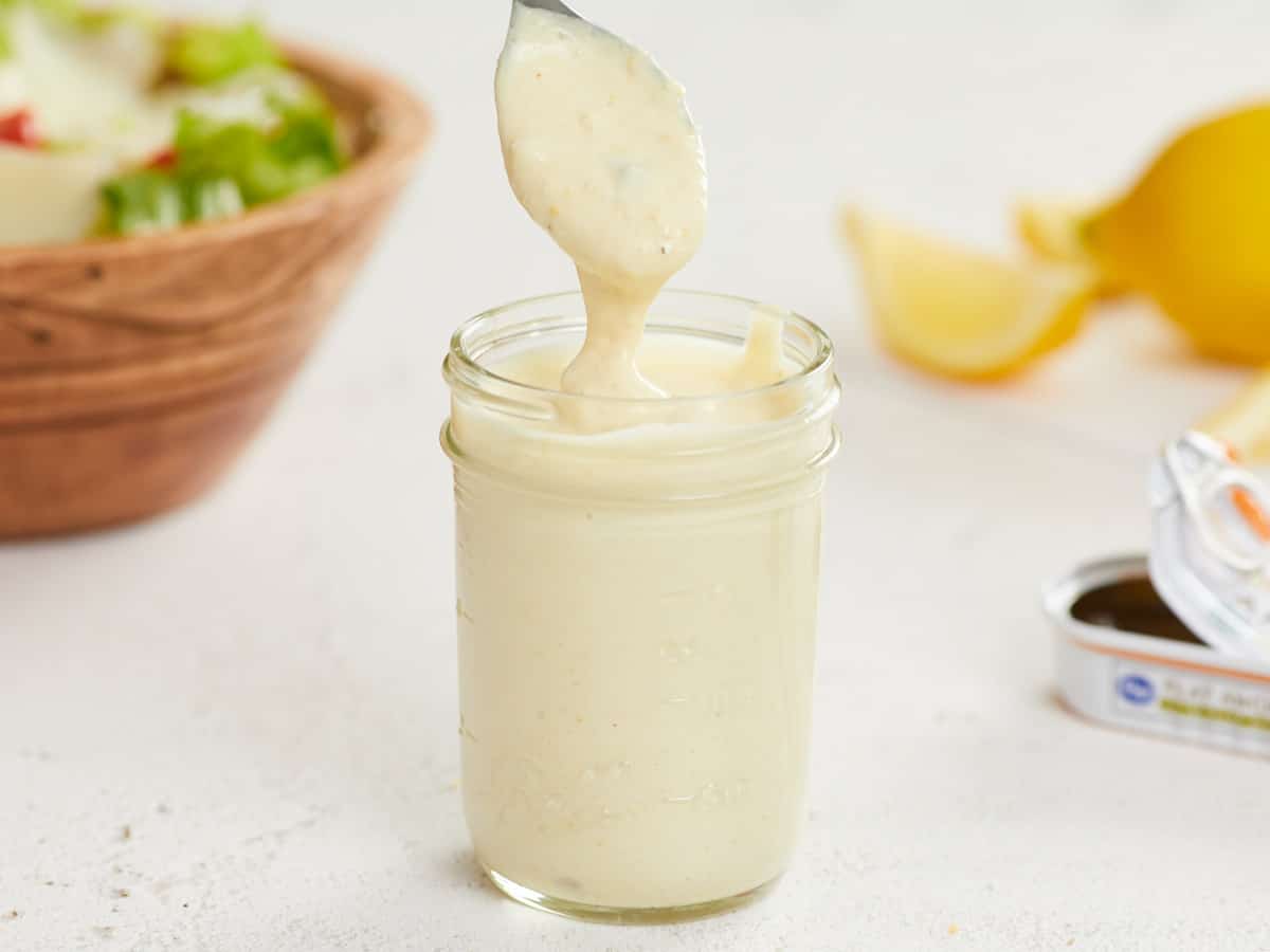 Vinaigrette César dégoulinant d'une cuillère dans un pot.