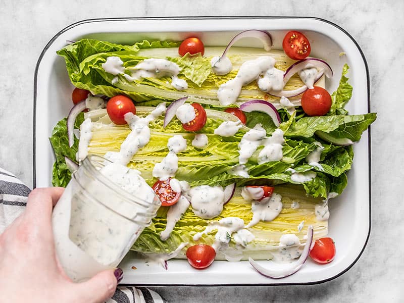 Vinaigrette ranch maison versée sur une salade romaine avec tomates et oignons rouges