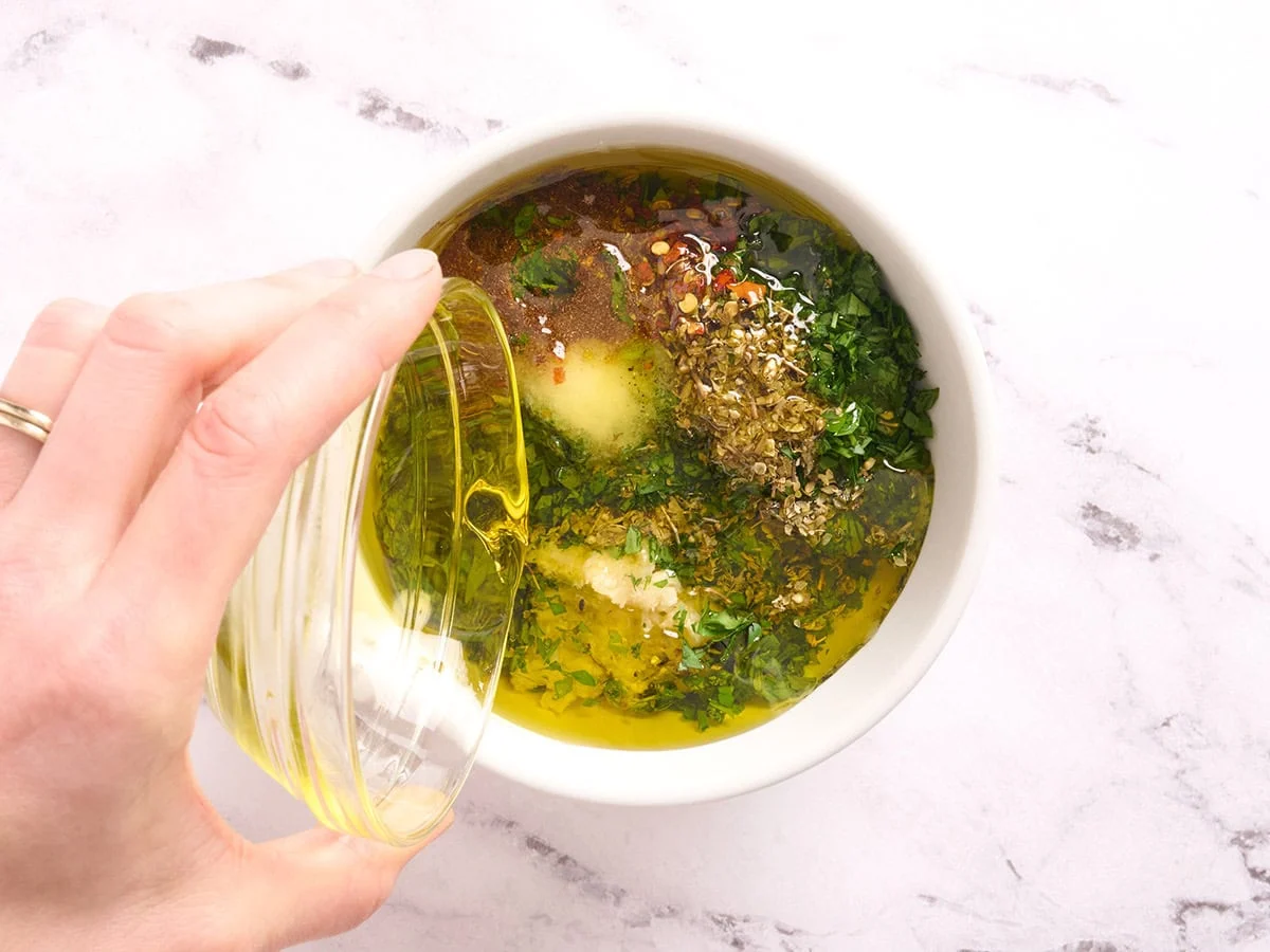 L'huile est versée dans un bol d'herbes, d'ail et d'épices.