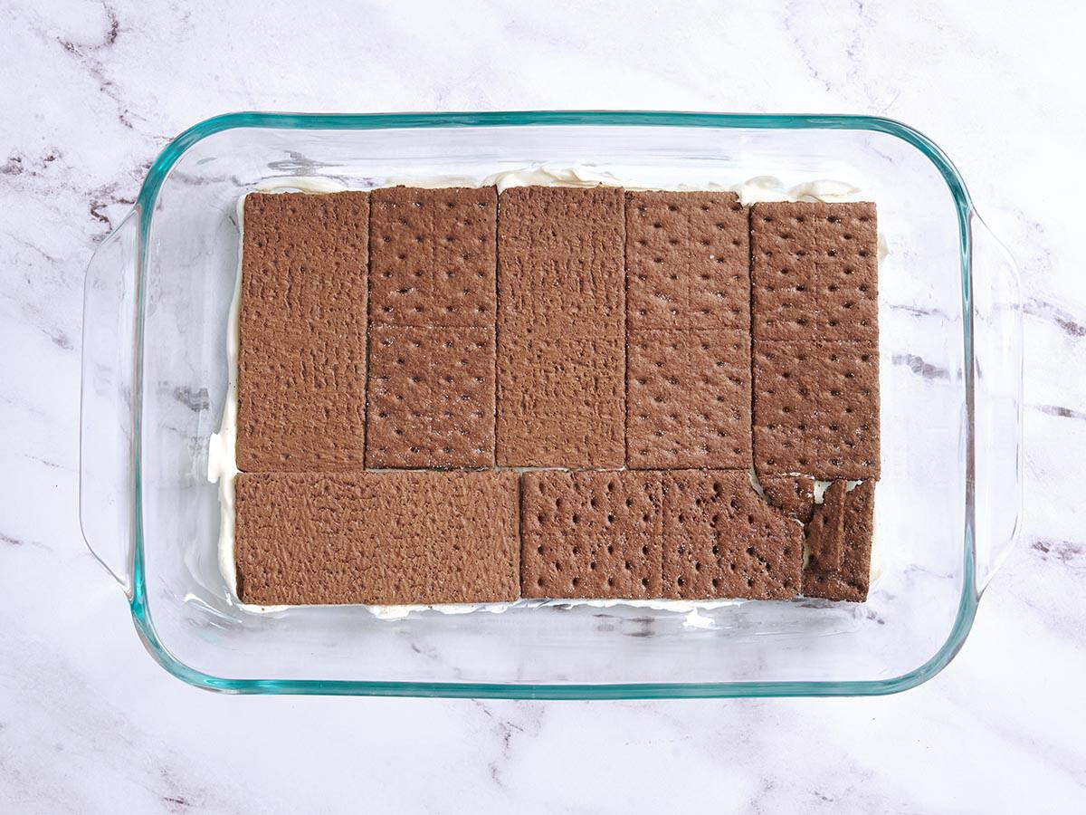 Une couche de biscuits Graham au chocolat ajoutée à un plat allant au four.