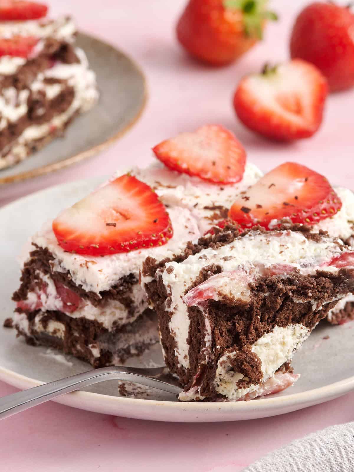 Vue latérale d'une tranche de gâteau glacé au chocolat et aux fraises avec une fourchette en prenant.