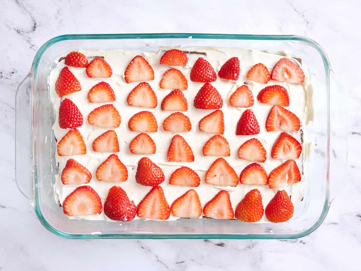 Fraises superposées sur un gâteau glacé au chocolat.