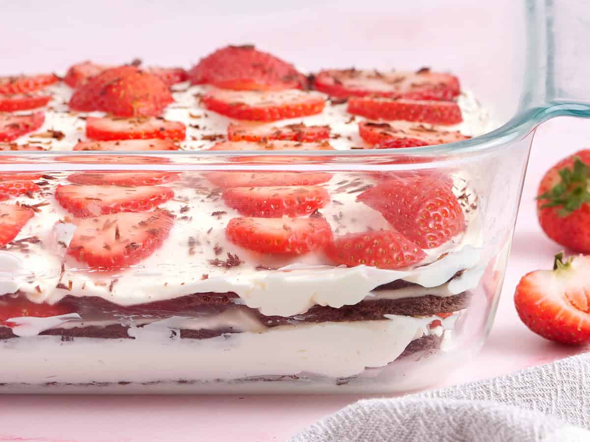 Vue latérale du gâteau glacé aux fraises et au chocolat dans un plat de cuisson en verre.