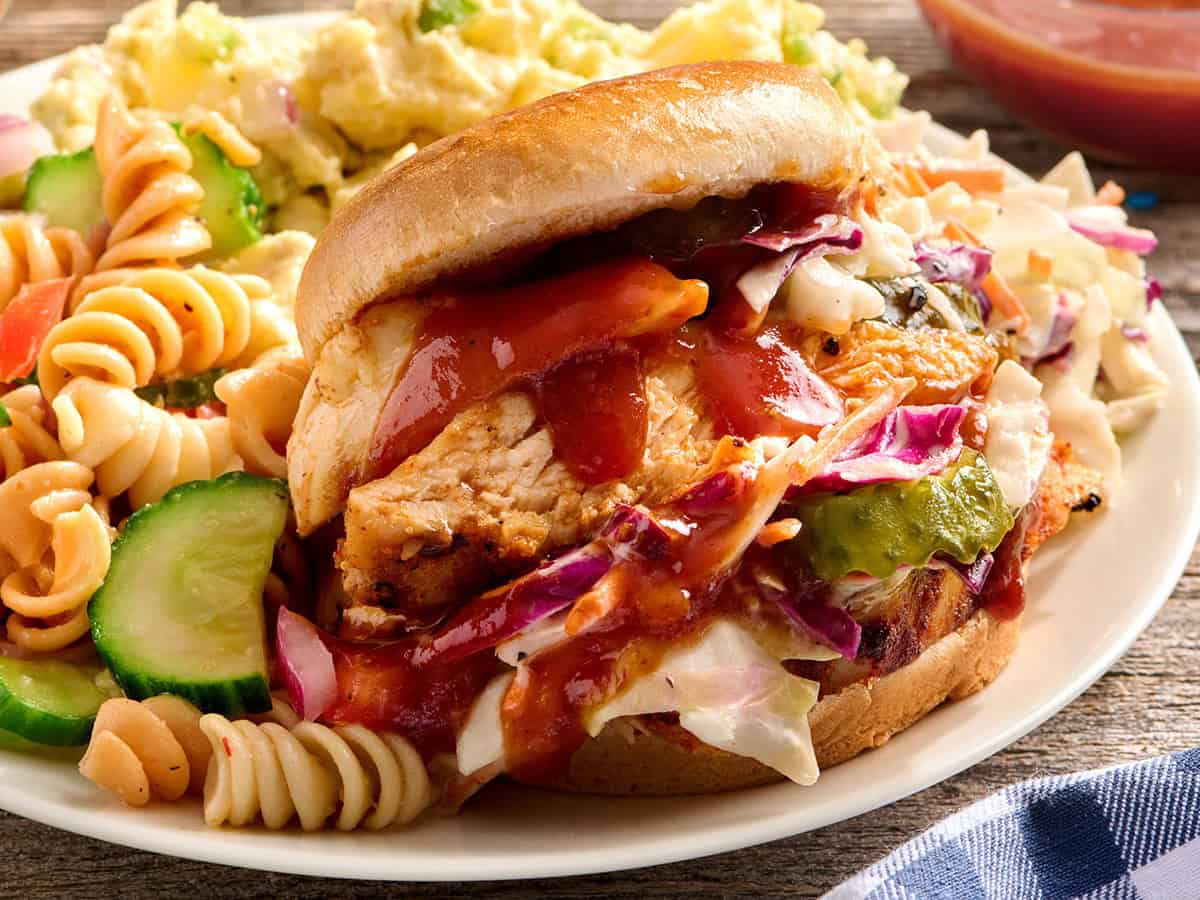 Vue latérale des sandwichs au poulet grillé sur une assiette avec salade de pâtes.