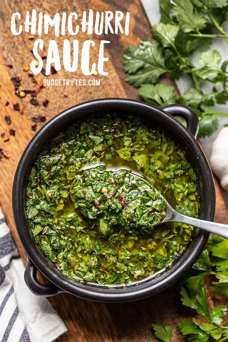 Un bol noir rempli de sauce chimichurri avec une cuillère en soulevant, gros plan.