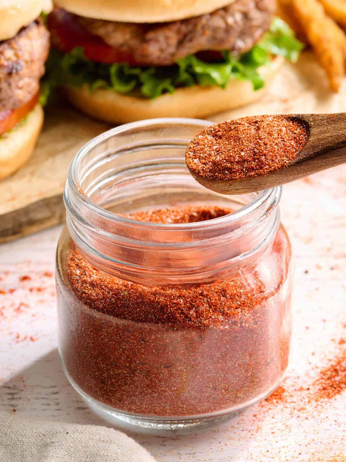 Vue latérale de l'assaisonnement pour hamburger fait maison dans un pot avec une cuillère.
