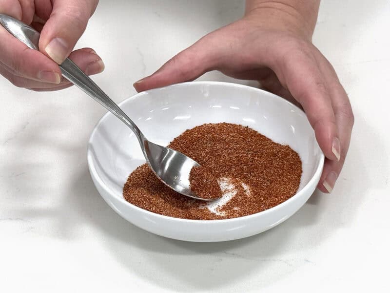 développeur de recettes en remuant l'assaisonnement pour hamburger maison dans un bol