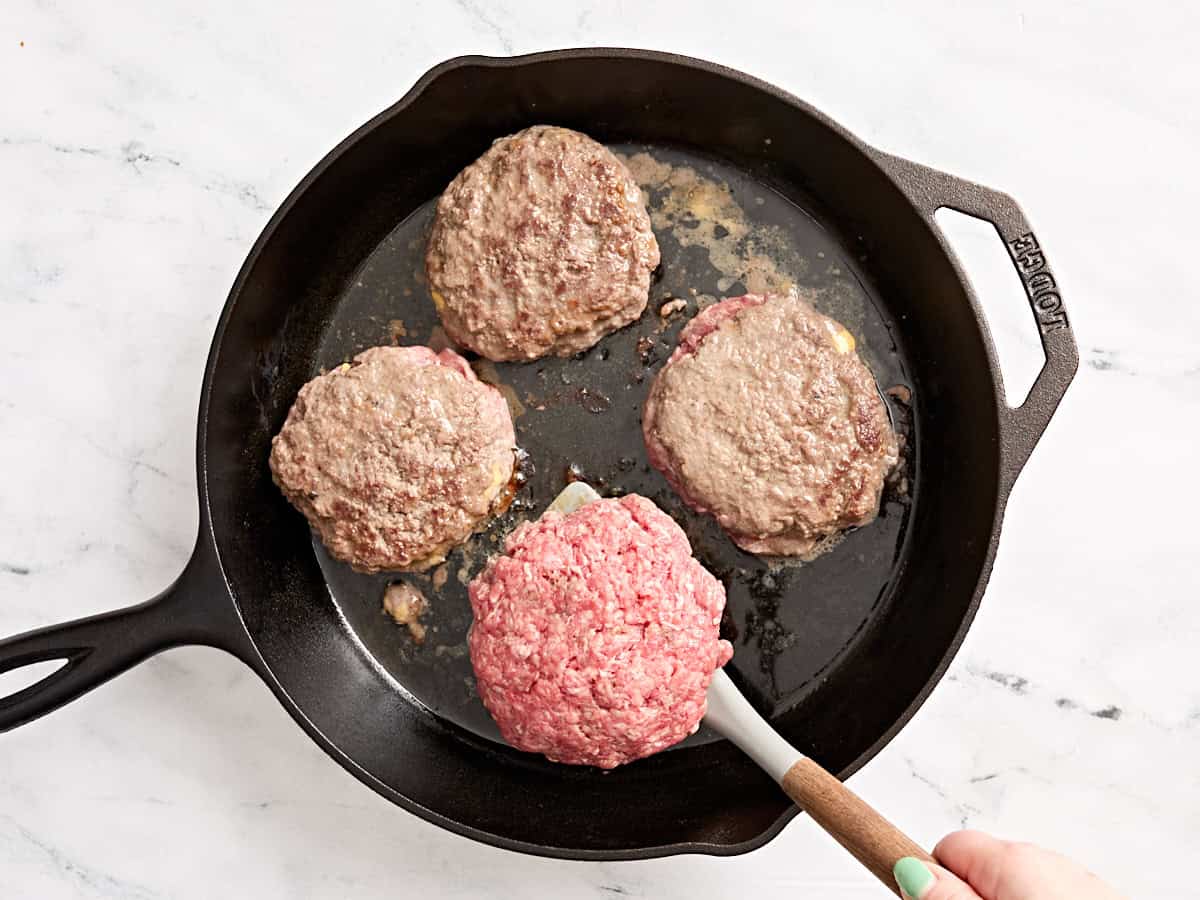 Galettes lucy juteuses retournées avec une spatule dans une poêle.