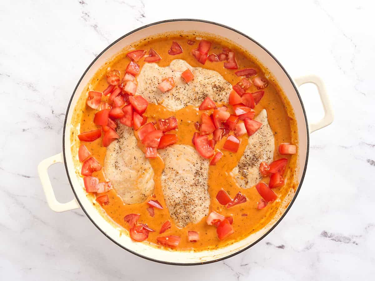 Tomates en dés ajoutées à une poêle de poulet crémeux aux tomates.