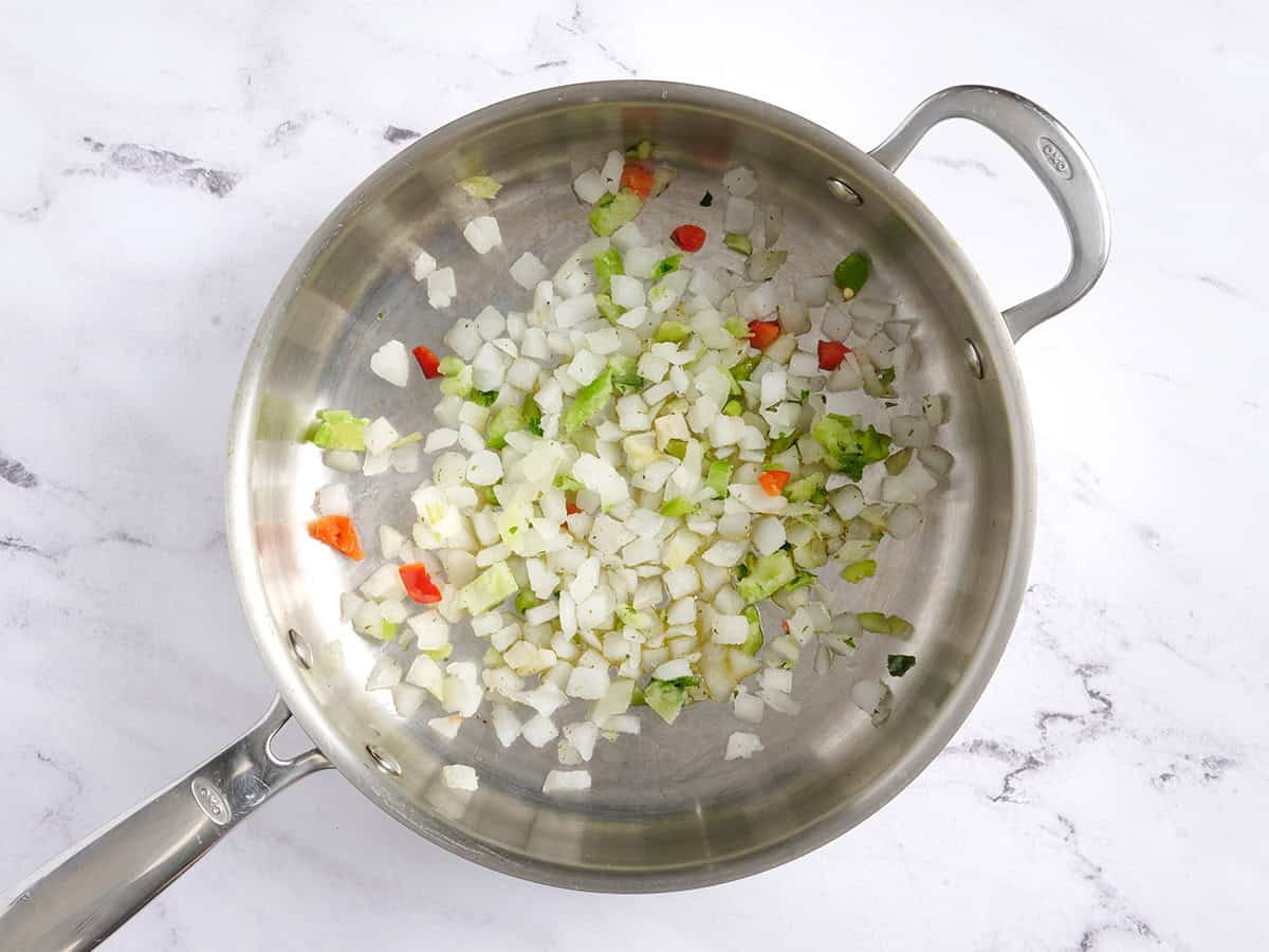 Poivrons et oignons surgelés coupés en dés dans une poêle.