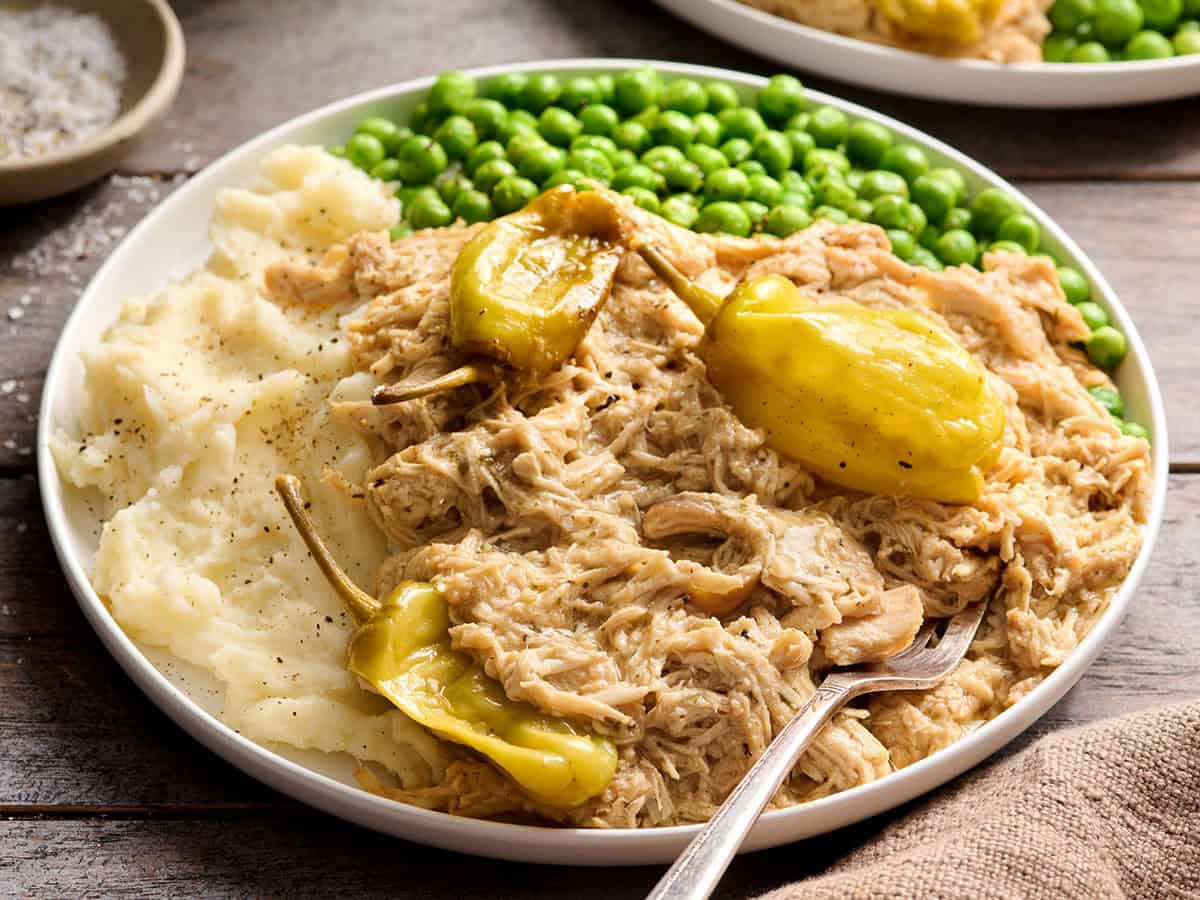 Poulet du Mississippi sur une assiette avec purée de pommes de terre et pois verts.